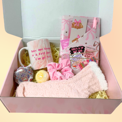 Gift box with a mug, snacks, and other items on a gradient background